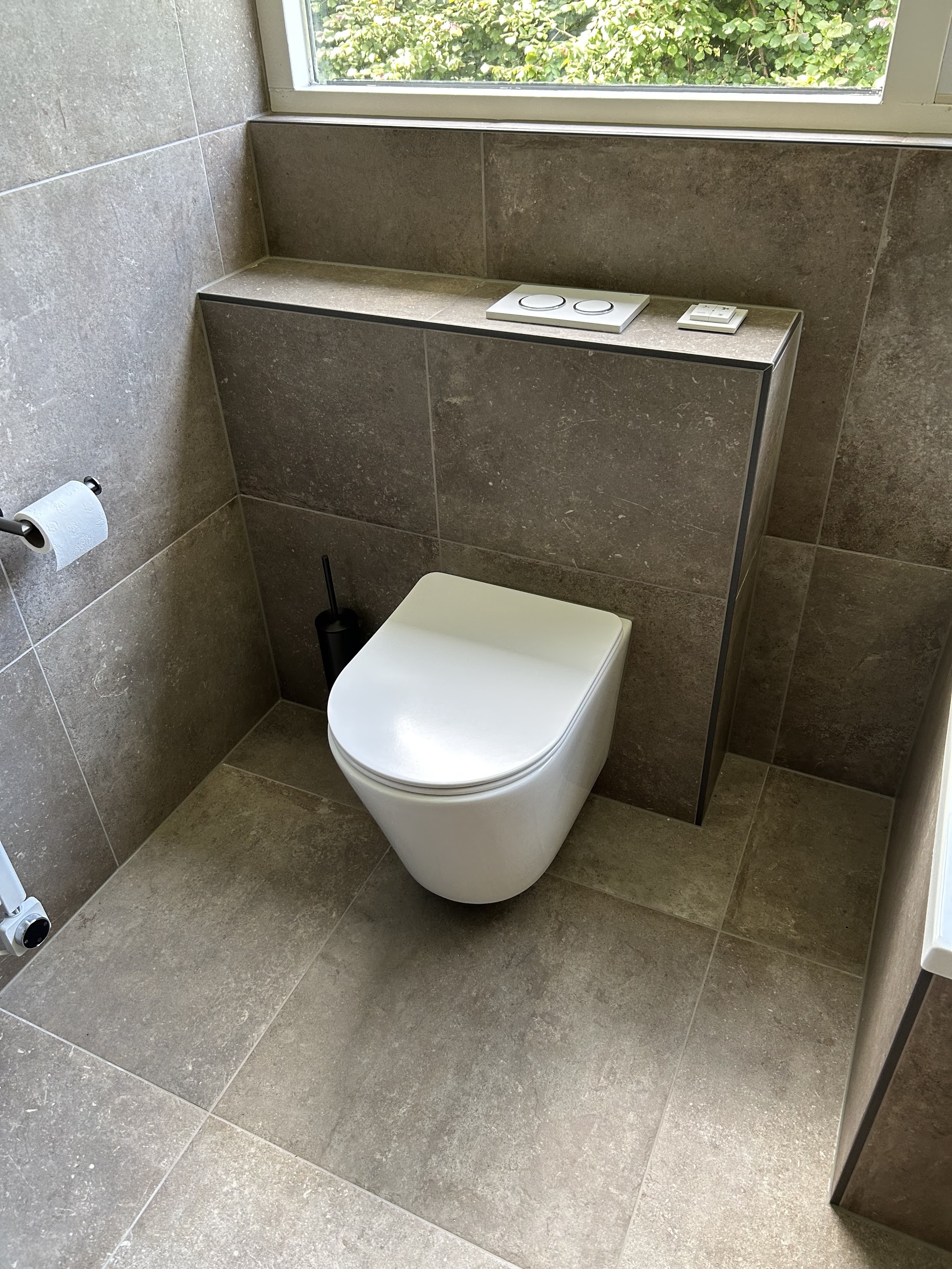 Hangend toilet met warme natuursteenlook tegels en inbouwreservoir