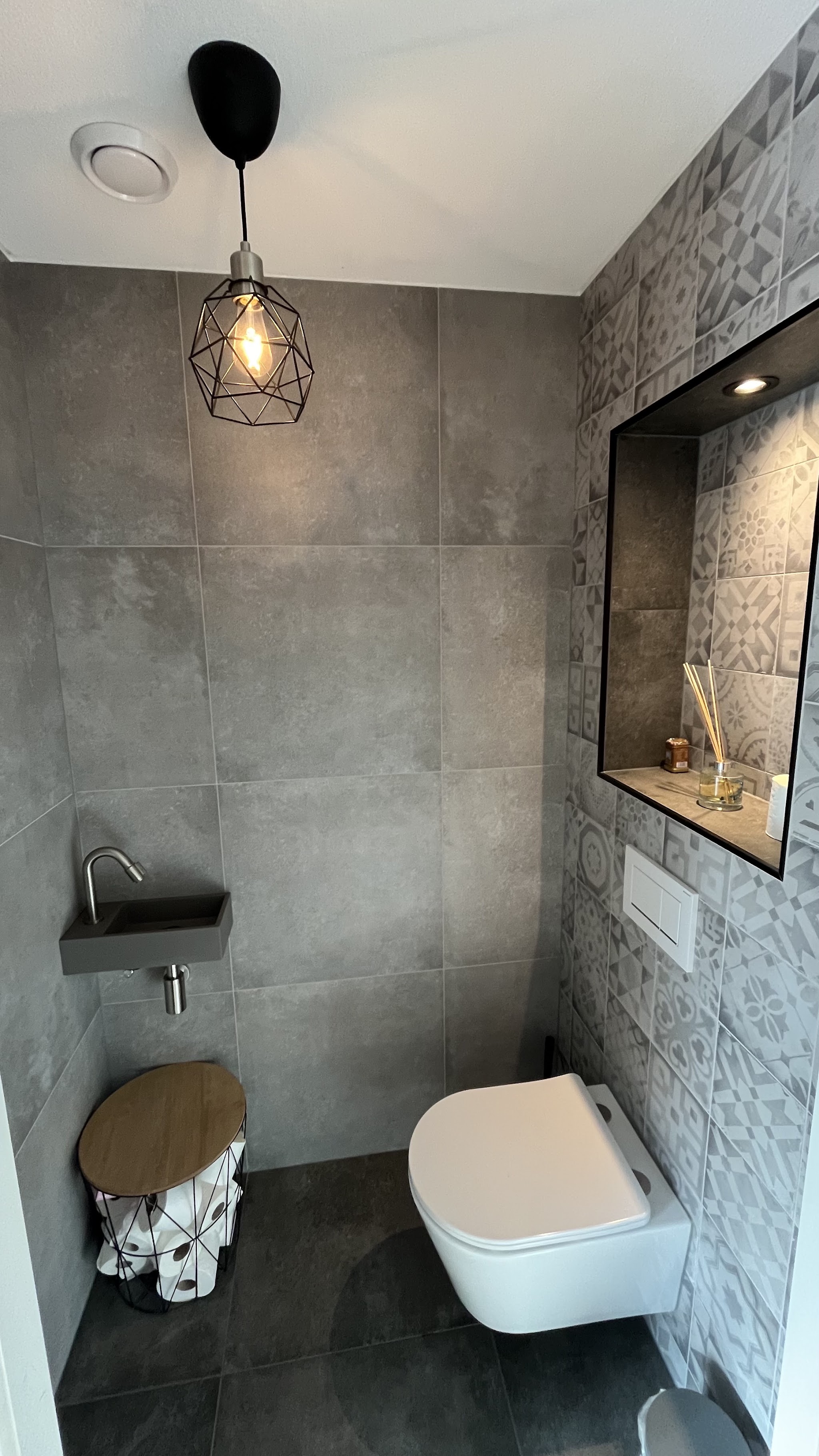 Decoratieve patroontegels rond een inbouwnis in een toiletruimte